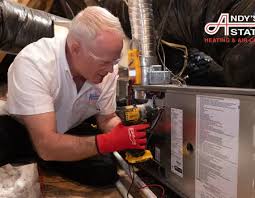 Technician wearing red gloves inspecting a furnace and its connected ductwork