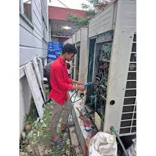 Technician in a red shirt servicing an outdoor HVAC cabinet
